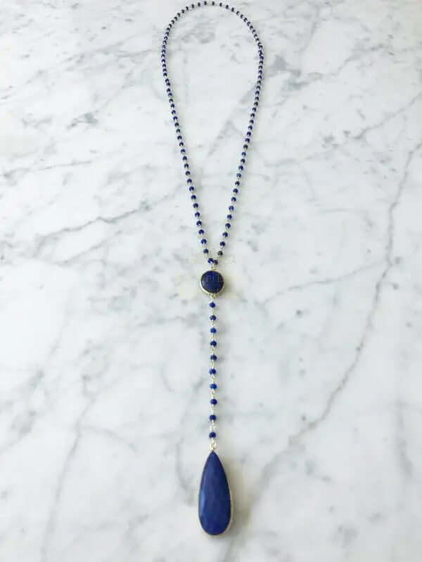 Diana Montecito sapphire necklace with sapphire drop displayed on a marble surface, showcasing its elegance and beauty.