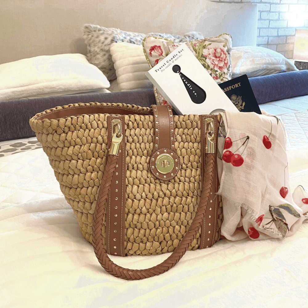 Travel Candle with Matches - Pomme Cider in a stylish bag with passport and book on a cozy bed.