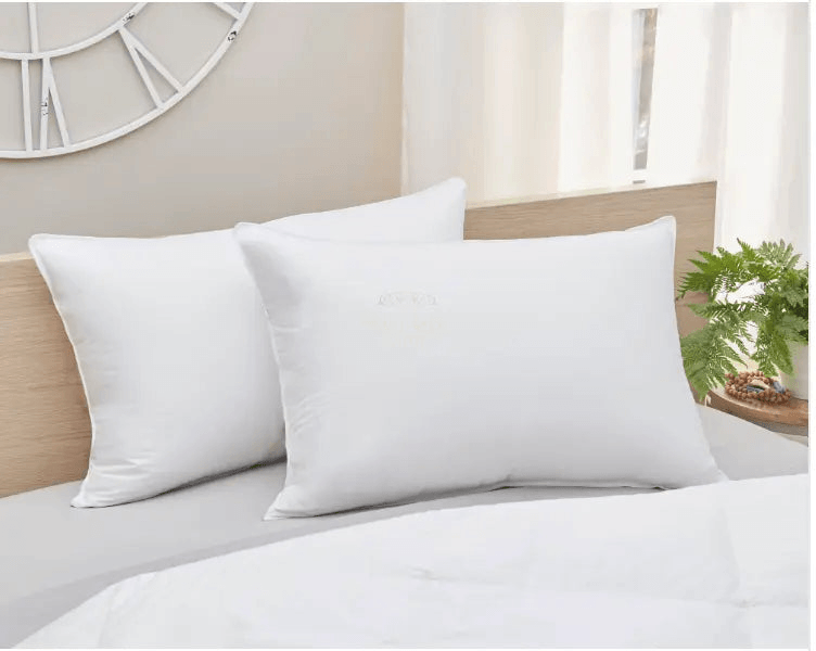 Luxury soft down pillow set on a neatly made bed with a light gray comforter and modern decor.