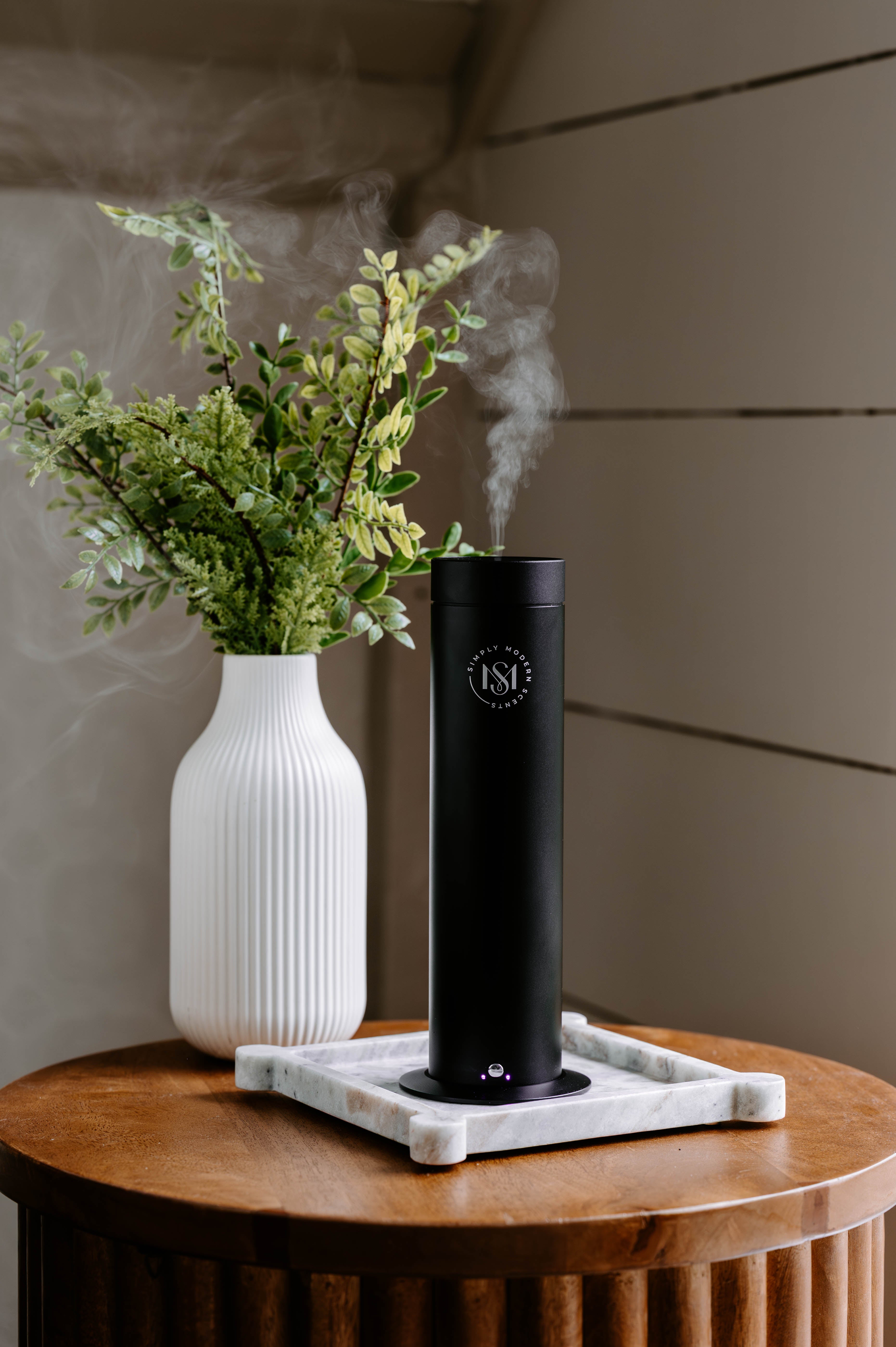 Luxury Electric Home Diffuser + Complimentary 2 OZ Diffuser Oil | SMS150 releasing soothing mist beside a decorative vase.