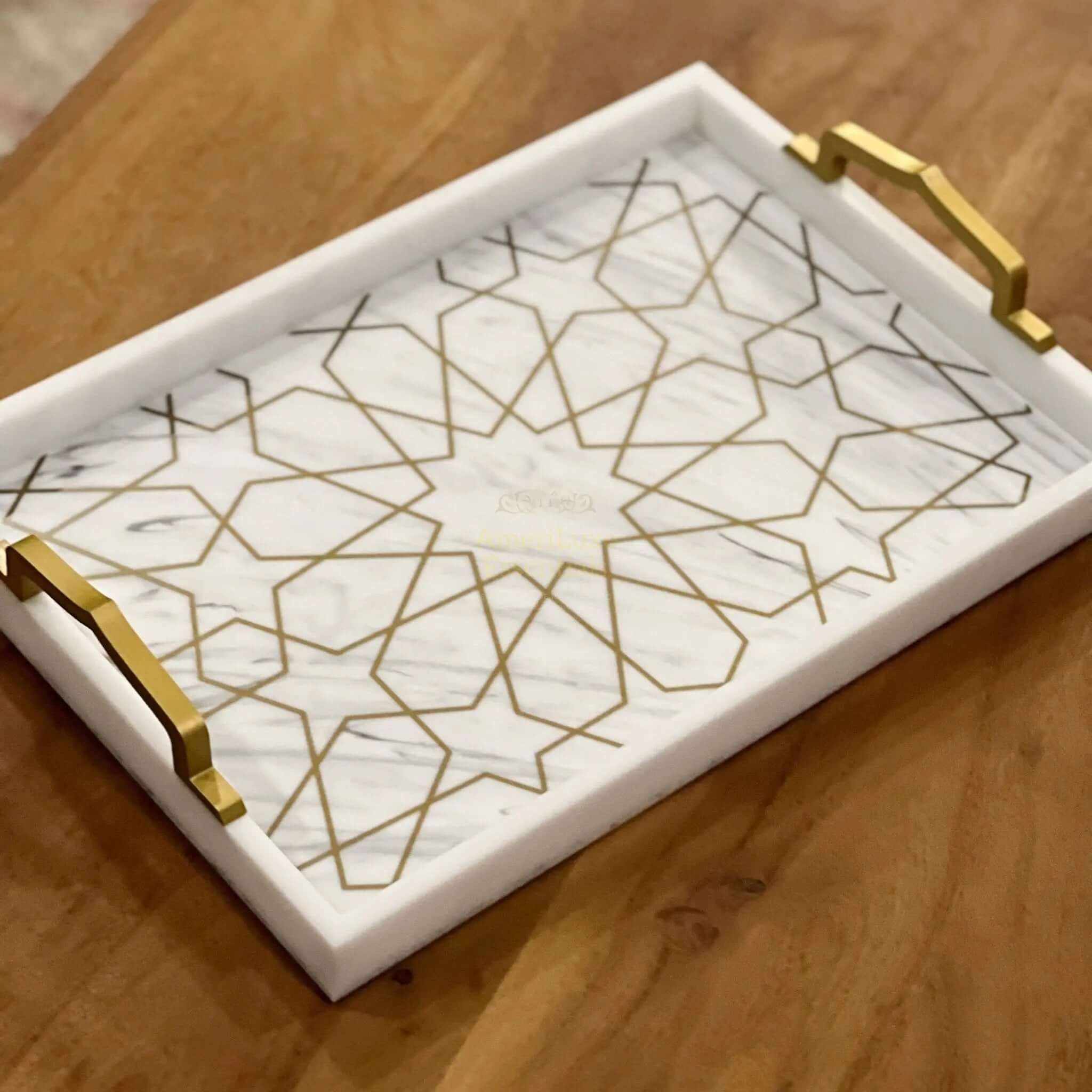 Elegant acrylic serving tray with gold handles and marble-inspired design on a wooden table.