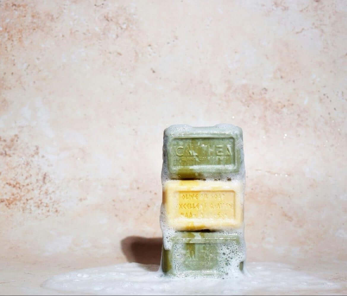 natural olive oil soap three pack with lavender and honey, displayed with suds on a textured background.