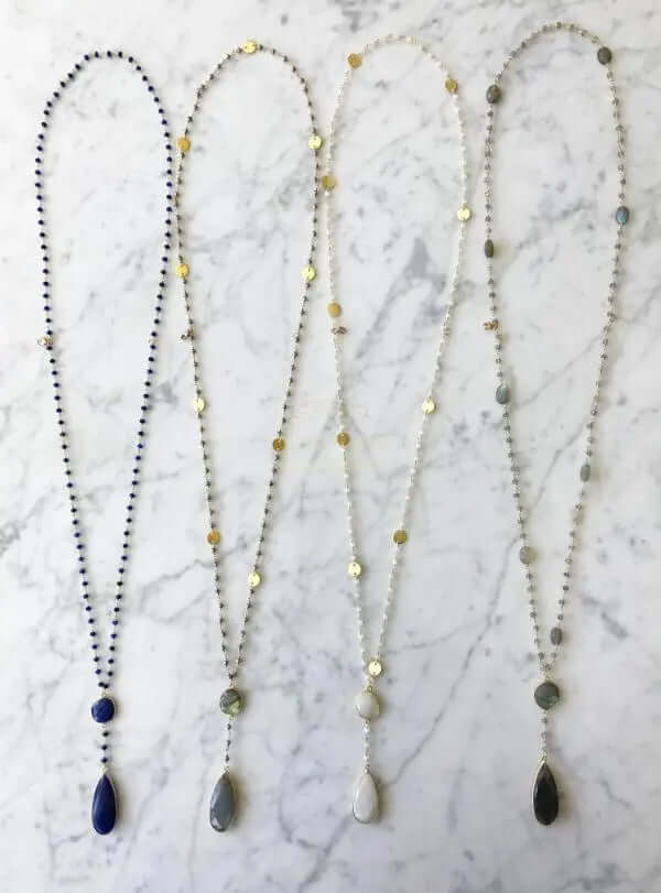 Double sapphire necklace collection featuring various gemstones and elegant designs on a marble background.