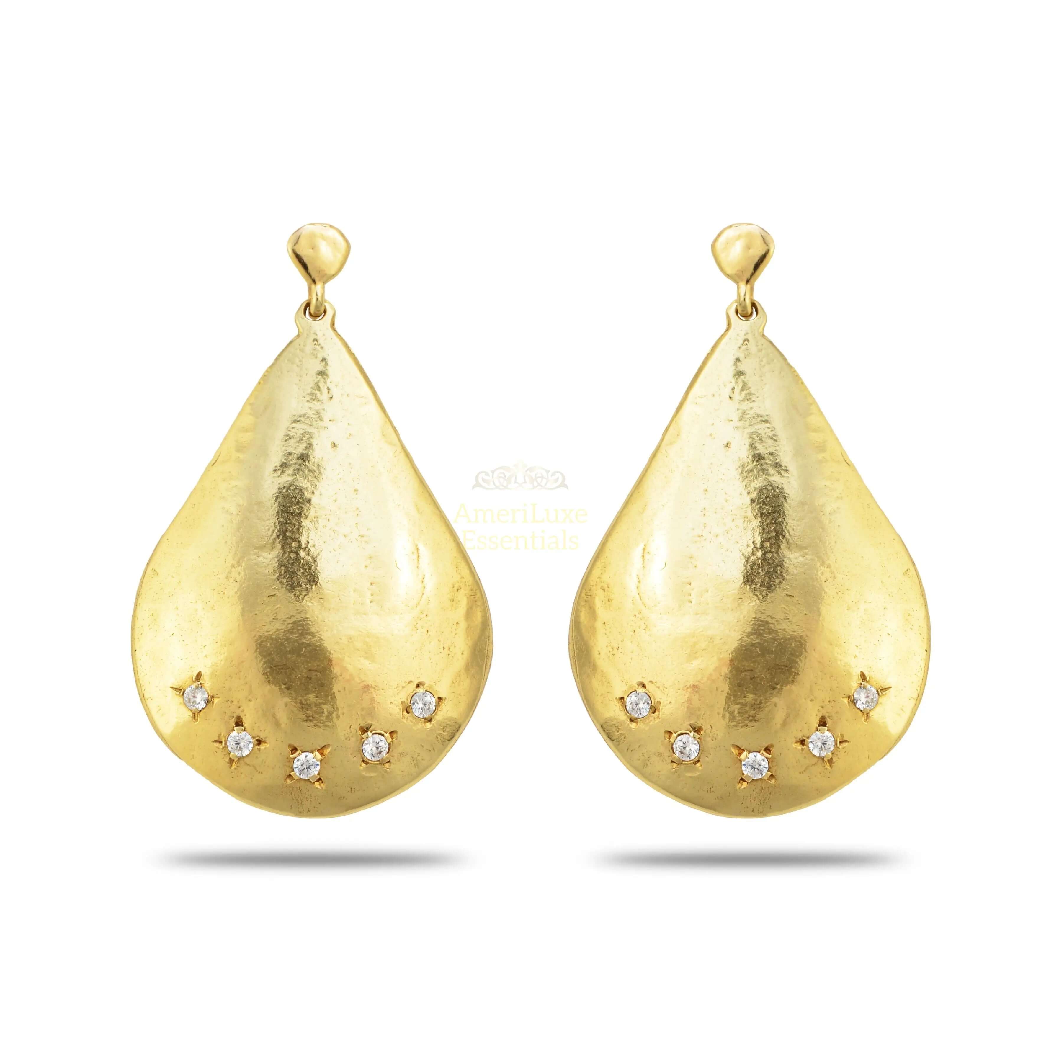 Parisian designer earrings featuring a teardrop shape with a smooth golden surface and sparkling accents.