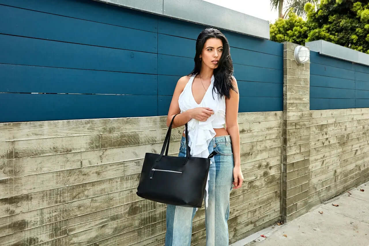 Mid Zip Tote Bag being showcased by a model against a modern wooden fence backdrop.