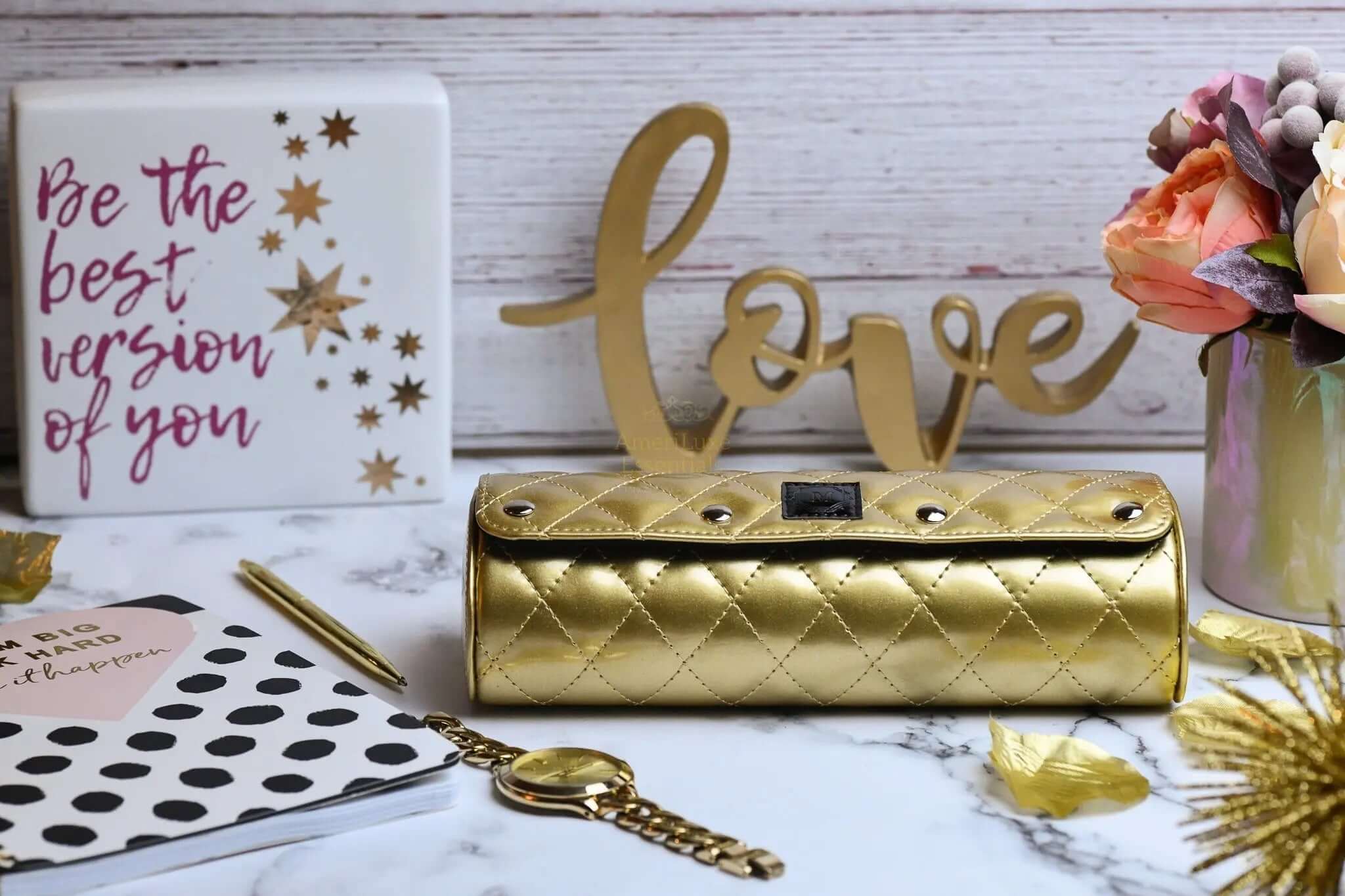 Limited edition women's watch case in glossy Royal Gold, elegantly displayed with accessories and floral decor.