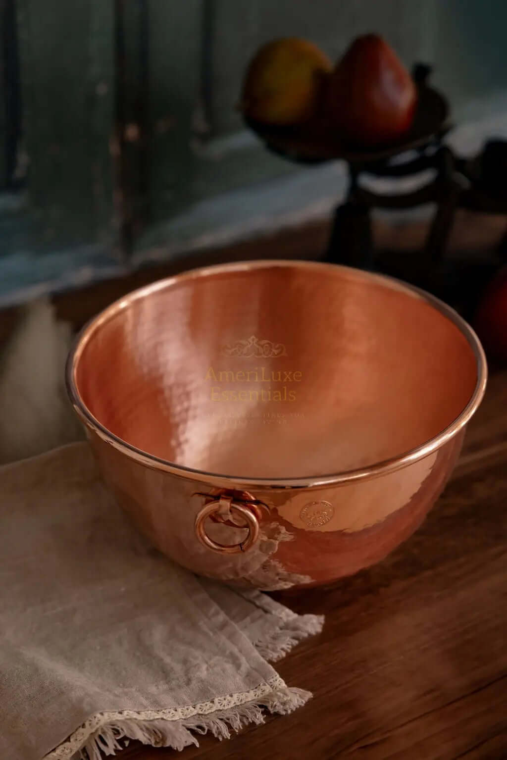 CMK Farmhouse Kitchen Copper Mixing Bowl on a wooden table with a rustic cloth and apples in the background.