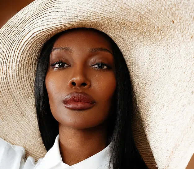 Stylish model wearing the Grand Belmont sun hat, showcasing its wide brim and chic design for summer fashion.